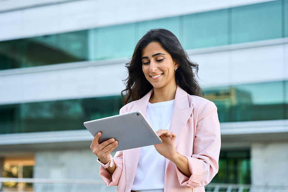 Banner of young middle eastern Israel businesswoman using tablet pc application for online remote work at office business building outdoors. Indian or arabic woman holding digital computer. Copy space