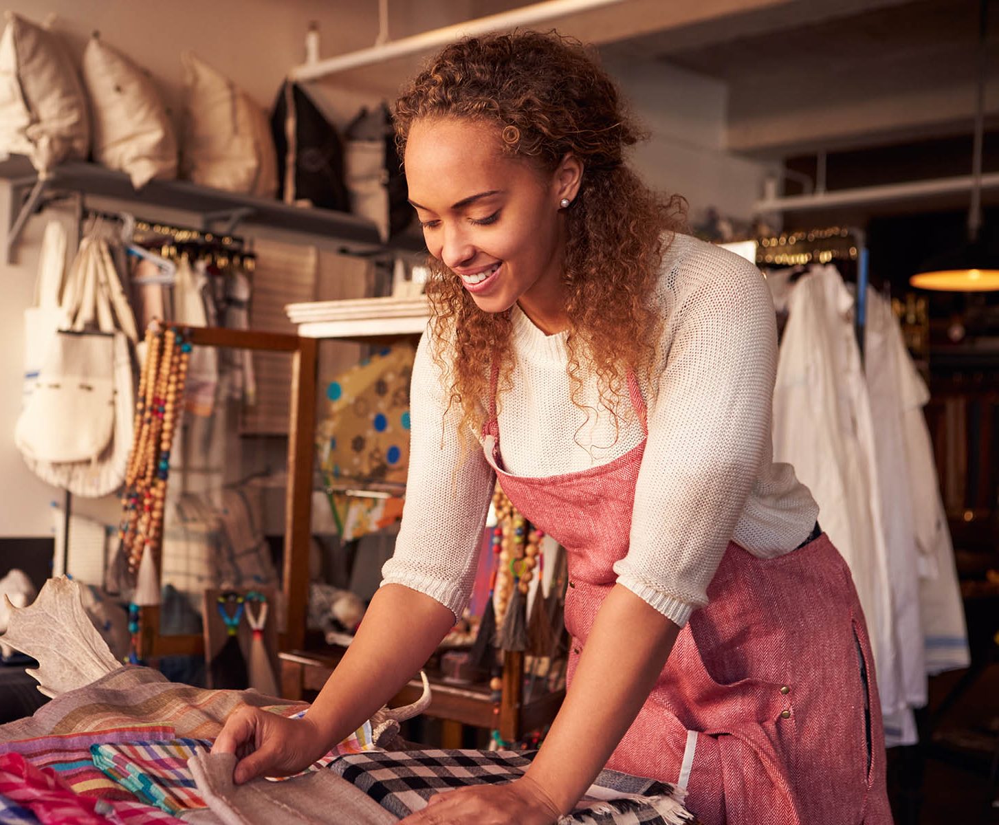 Female Sales Assistant Arranging Textiles In Homeware Store
