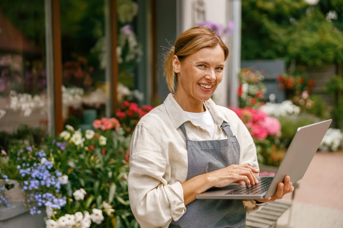 Flower shop owner wearing an apron working on a laptop in her store