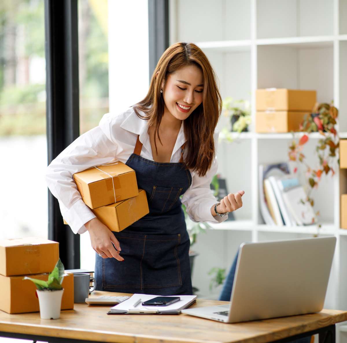 Small business owner packing boxes next to an open laptop