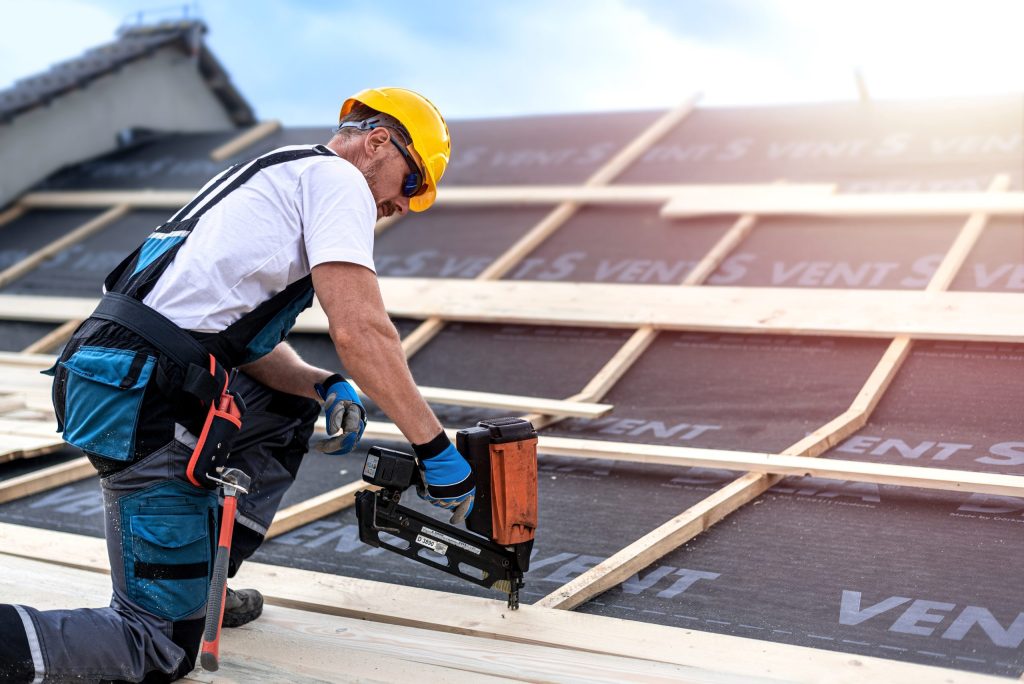 Carpenter nailing a timber board using an electric nailer